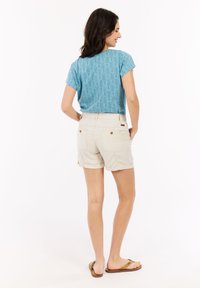 Lichtblauw gestreept T-shirt met korte mouwen, gecombineerd met crèmekleurige cargoshorts. De shorts hebben twee achterzakken en opgerolde zoom.