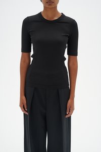 Melnā ribota īsās piedurknes blūze ar apaļu kakla izgriezumu. Pieguļošs dizains, gluda tekstūra, saskaņota ar brīvām melnām biksēm.