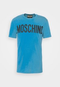 Modrá krátkosrstá pánská tričko Moschino s velkým černým logem značky přes hruď.