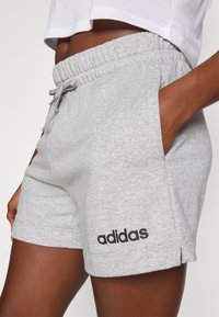Szürke sportnadrág elasztikus derékpánttal, oldalsó zsebekkel és egy fekete "adidas" logóval az alsó bal oldalon. Puha anyagú, kényelmes fazon.