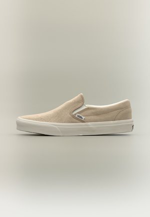 Μπεζ παπούτσι Vans χωρίς κορδόνια με λευκή λαστιχένια σόλα και πλαϊνές ελαστικές πάνελ σε ουδέτερο φόντο.