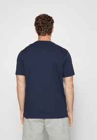 T-shirt in cotone blu navy con scollo rotondo e maniche corte, mostrato da dietro, caratterizzato da una texture liscia e una vestibilità comoda.