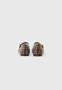 Brown leather shoes featuring a studded design with silver studs. Flat sole and slip-on style with a rounded toe.