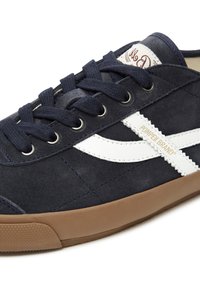 Tamno plavi zimski tenisice od plavog nubuka s bijelim kožnim prugom, okruglim vrhom, ravnim gumeni potplat i metalnim rupicama. Ima smešani gumeni potplat.