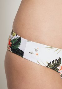 Parte de baixo de biquíni floral com base branca adornada com folhas verdes e flores laranja. Tecido suave com design de cintura baixa e faixa larga.