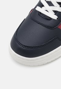 Granatowy skórzany sneaker z białymi sznurówkami, o gładkiej fakturze, z kontrastującymi bordowymi akcentami i białą gumową podeszwą.