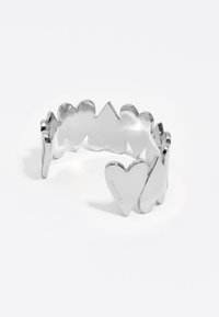 Pulsera de muñeca en forma de corazón de plata, con picos y valles alternos, que presenta una superficie lisa y pulida y un grabado sutil.