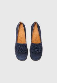 Navy suede flats with a floral appliqué on the toe, smooth texture, rounded toe, and brown leather insole, designed for comfort.