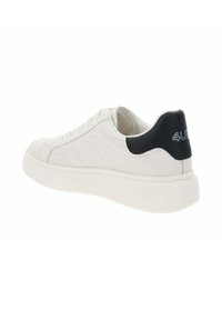 Baskets en cuir blanc avec une semelle texturée, bout rond et accent de talon noir présentant un logo en relief. Design multipanneau avec des coutures discrètes.