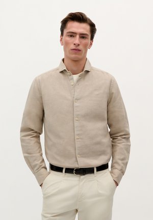 Cămașă bej deschis cu guler, având un material texturat, o ușoară strălucire și un logo mic pe piept. Asortată cu pantaloni ușori.