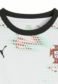 Vit sporttröja med grön och röd prickig mönster, svart ribbad krage, med Puma-logotyp och Portugals nationalemblem.