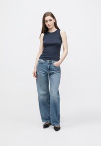 Top smanicato color navy abbinato a jeans a gamba larga color azzurro chiaro con dettaglio vissuto e tasche frontali, completato da tacchi neri.