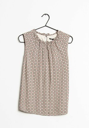 Sleeveless blouse with geometric diamond print in white, red, and black, hanging on a black hanger against a white background.