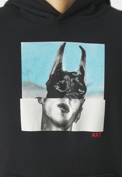 Haut à capuche noir avec un graphique d'une figure masquée aux oreilles pointues superposée sur un fond coloré, étiqueté "ART" en rouge.