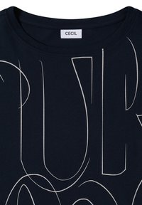 T-shirt bleu marine foncé à col rond avec de fines lignes blanches abstraites et une étiquette blanche portant l'inscription "CECIL" au niveau du col.