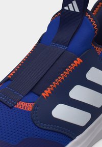 Μπλε αθλητικό παπούτσι με πορτοκαλί ζιγκ-ζαγκ ραφές, ελαστικό ναυτικό λουράκι και λευκές ρίγες Adidas στο πλάι.