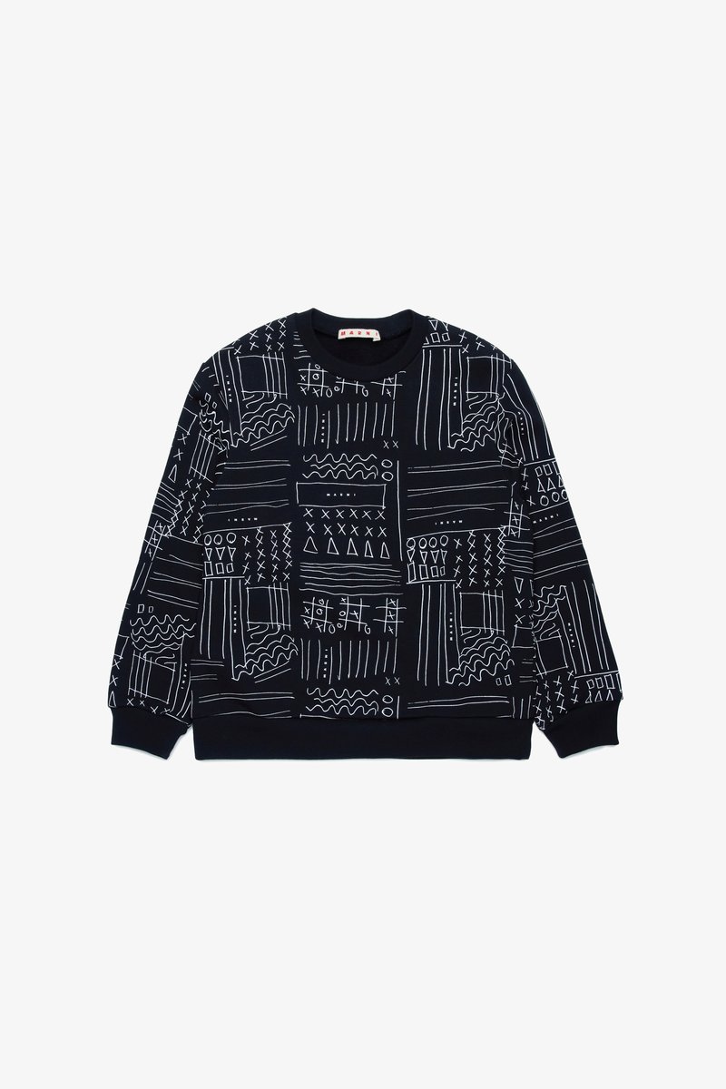 Melns džemperis ar baltām abstraktām rakstām, ribotām piedurknēm un apakšmalu, apaļu dekoltē un brīvu piegriezumu. Izgatavots no mīksta, elpojoša auduma.