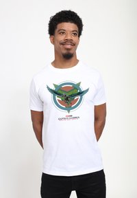 Camiseta blanca de algodón con un gráfico colorido de un personaje alado con acentos circulares y triangulares, rodeado de texto.