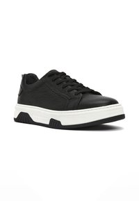 Sneaker in pelle nera con superficie testurizzata, punta rotonda, suola intermedia bianca e suola esterna in gomma nera; presenta un classico design con lacci.
