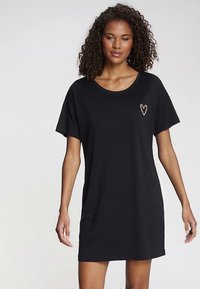 Schwarzes T-Shirt-Kleid mit kurzen Ärmeln, rundem Halsausschnitt und einem kleinen goldenen Herzdetail auf der linken Brust. Weicher, leichter Stoff.