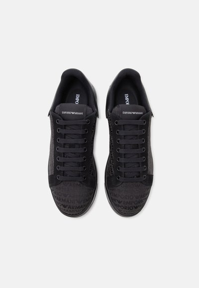 Paire de baskets noires Emporio Armani avec lacets, logo sur la languette et dessus en tissu à motifs.