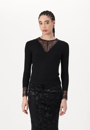Black long-sleeve top featuring a lace front panel and lace trim on sleeves, paired with a textured black floral skirt.
