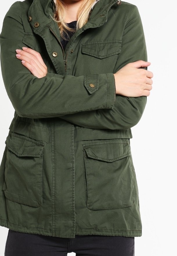 Chaqueta parka verde oliva con capucha, cierre frontal con cremallera, dos bolsillos en el pecho y cintura fruncida. Presenta tela suave y detalles en botones como adornos.