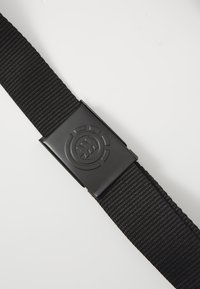 Black nylon webbing belt featuring a rectangular plastic buckle with a circular logo pattern. Smooth texture and adjustable length.