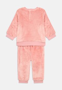 Set da loungewear in pile rosa, con maniche lunghe e polsini elasticizzati, morbido al tatto, composto da una maglia a girocollo e pantaloni coordinati.