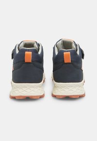 Zapatillas deportivas de color azul marino con acentos en naranja y parte superior texturizada, que cuentan con un cuello acolchado y una suela texturizada de color claro.