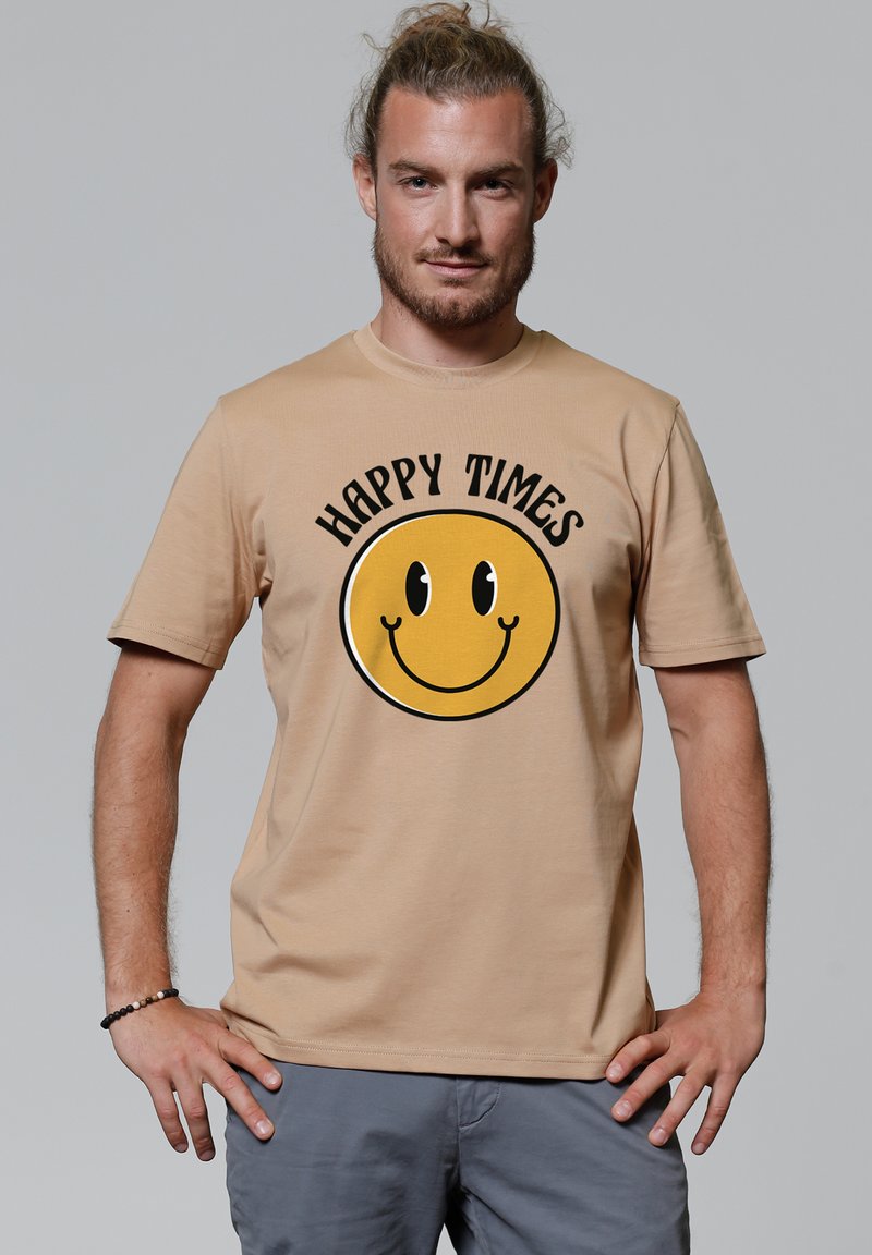 Beige katoenen t-shirt met een grote gele lachende gezicht grafiek met zwarte omranding en tekst "HAPPY TIMES" erboven. Korte mouwen.