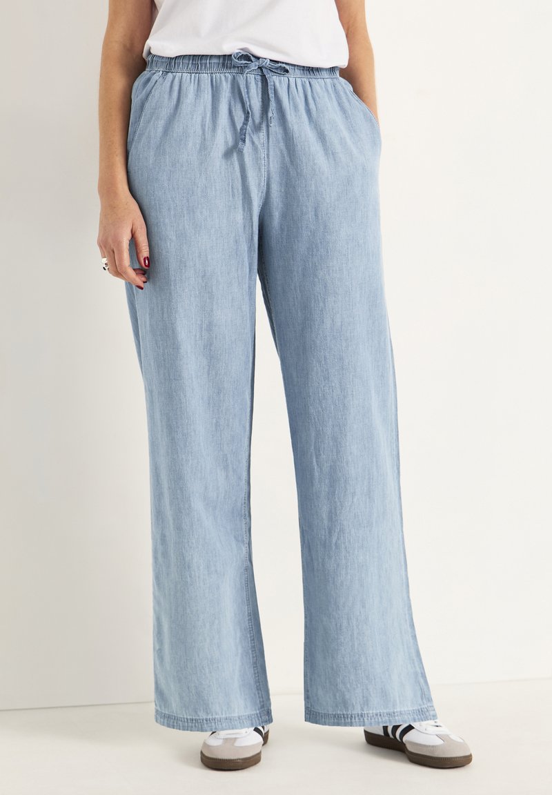 Ljusblå, lätt och flödande byxor med vida ben i denimtyg. Har ett elastiskt midjeband med dragsko, två sidofickor och en avslappnad passform.