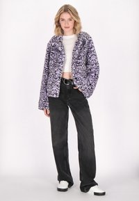 Faux fur-jacka i lavendel med ett leopardmönster, med långa ärmar och öppen framtill, tillsammans med högmidjade svarta jeans.