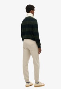 Groen en zwart gestreepte longsleeve shirt met een witte kraag, gecombineerd met beige trainingsbroek. Casual schoenen maken de outfit compleet.