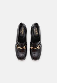 Black leather loafers with a glossy finish, featuring a gold chain accent across the front and cushioned insoles for comfort.