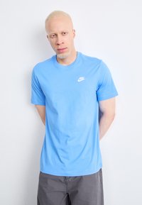 Svijetloplavi pamučni T-shirt s okruglim izrezom i kratkim rukavima, s malim bijelim Nike logotipom na lijevoj strani prsnog koša.