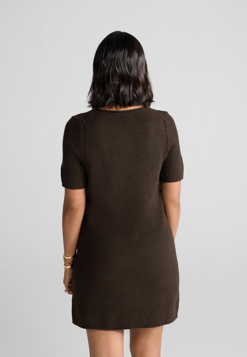 Braunes Strickkleid mit kurzen Ärmeln, rundem Ausschnitt, figurbetontem Schnitt und geripptem Saum. weiche Textur mit minimalen Details.