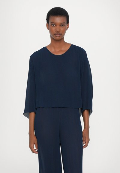 Mørkeblå cropped top med ribbet tekstur, rund udskæring og løse, brede ærmer. Sammen med matchende mørkeblå brede bukser.