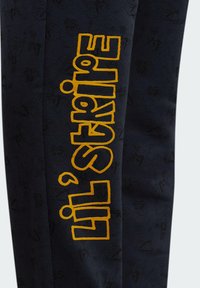 Dunkelblaue Sweatpants mit einem strukturierten Muster und fettem gelben "lil'stripe"-Text an der Seite. Hergestellt aus weichem Stoff.