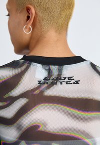 Black mesh shirt featuring a multicolored abstract pattern, with a stitched "LOVE UNITES" logo at the back near the collar.