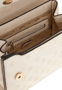 Borsa a mano in crema con motivo in rilievo, hardware dorato, tasca interna con zip e fodera con logo del marchio. Presenta una forma strutturata e bordi a contrasto.