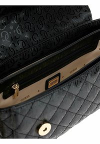 Sort quiltet håndtaske med et mønstret ydre, guldfarvet hardware og et foret indre med en lynlåslomme. Brandlogo synligt.