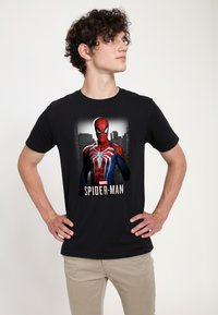 Svart bomullströja med en detaljerad Spider-Man-grafik i rött, blått och svart, med en stadslandskapsbakgrund och texten "Marvel SPIDER-MAN".