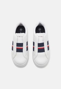 Tenisi albi tip slip-on cu un finisaj mat,benzi elastice bleumarin cu accente roșii și un logo pe limba pantofului. Talpă din cauciuc texturat.