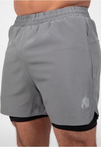 Grijze sportkorte broek met een elastische tailleband, voorzien van een kleine gorillagrafiek en een steekzak. Textuurstof met een nauwsluitende binnenlaag.
