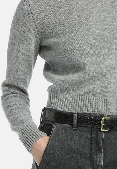 Grijze gebreide trui met geribbelde boorden en zoom, gecombineerd met een zwarte leren riem met krokodillenstructuur en een gouden gesp, gedragen met donkere jeans.