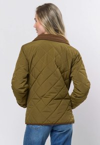 Brūni apkaklīts, olīvzaļš, kviltēts džakets ar teksturētu virsmu, kam raksturīgs dimanta raksts, garām piedurknēm un apaļu apakšu.