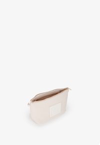 Gestructureerde crèmekleurige leren tas met een ritssluiting, voorzien van een gemold logo aan de voorkant en een lichte interieur.