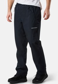 Schwarze wasserdichte Hose mit elastischem Bund, seitlichen Reißverschlusstaschen und reflektierenden Akzenten für Sichtbarkeit in Außenbereichen.