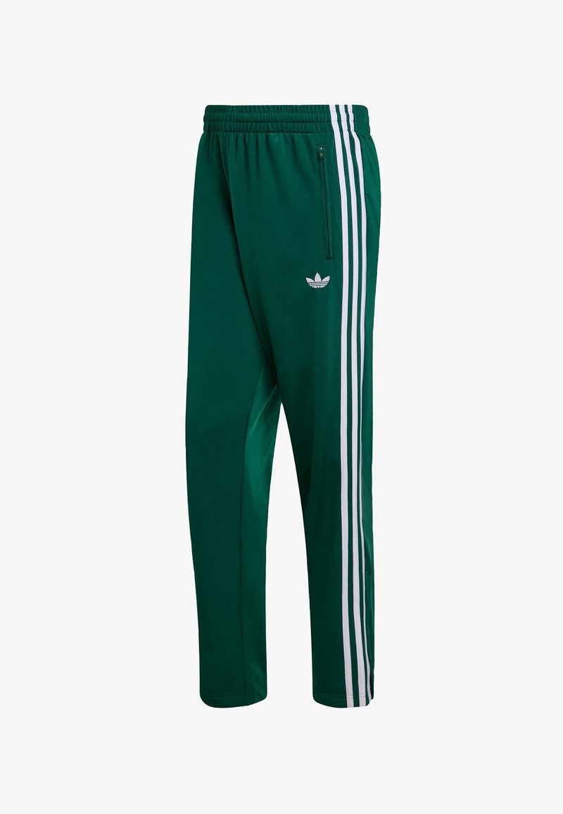 Grüne Sporthose mit einem Reißverschlusstaschen, versehen mit drei weißen vertikalen Streifen an den Seiten und einem kleinen Logo nahe dem Bund.